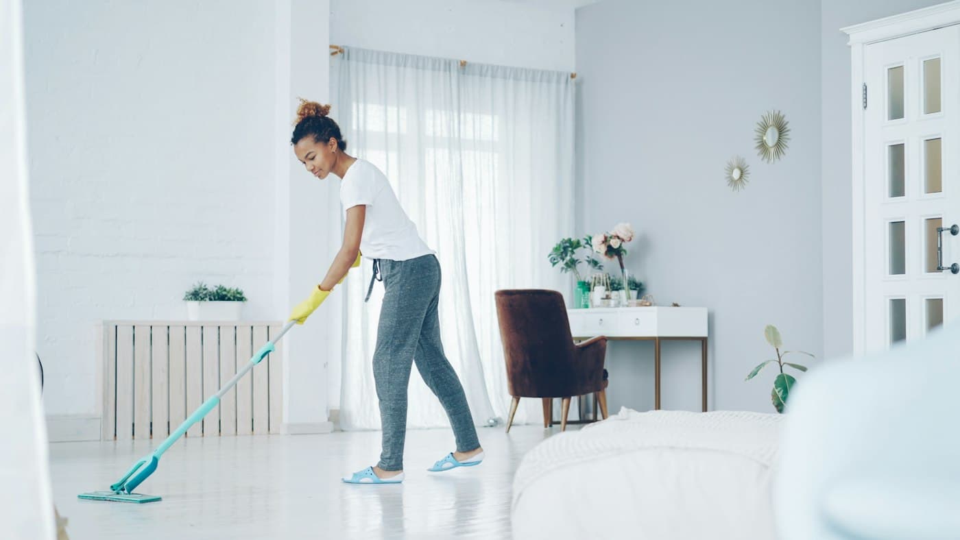 A cleaner mopping the floor of a bright living room
